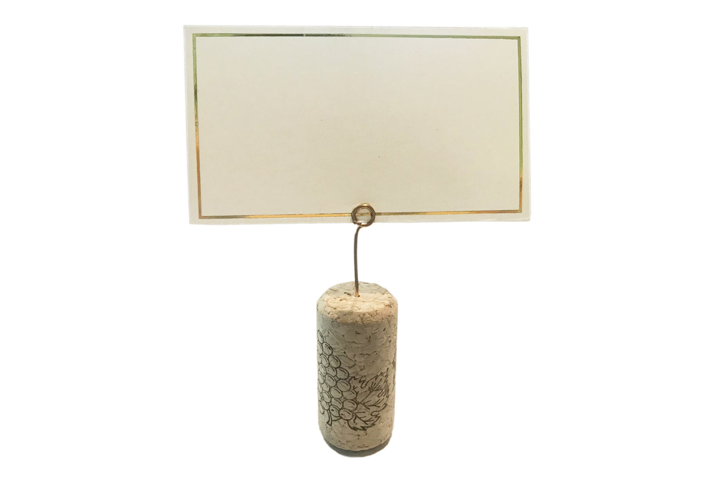 Close-up of mini round gold wire place card clip in a wine cork with a white card inserted.